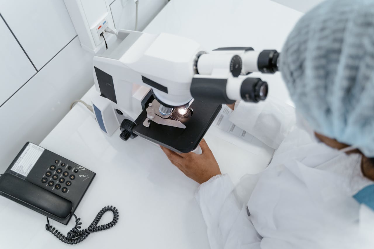 Scientist in lab coat observed using a microscope for research.